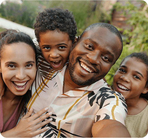 Family of four smiling for a selfie outdoors